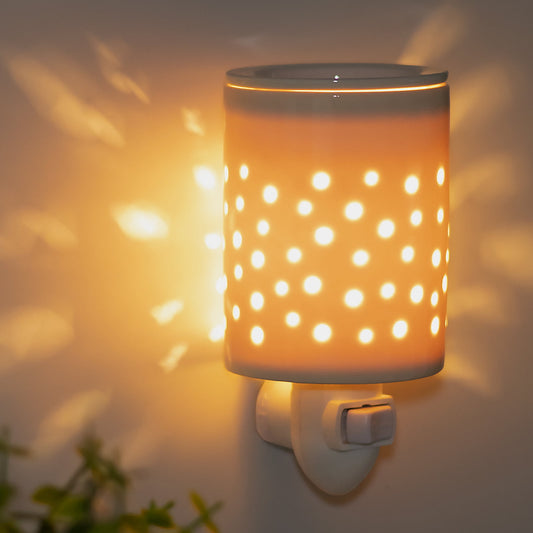 Plug-in electric wax melt warmer plugged into a wall outlet
