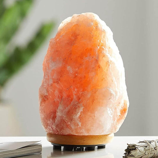 Hand-carved pink Himalayan salt lamp glowing on a wooden base