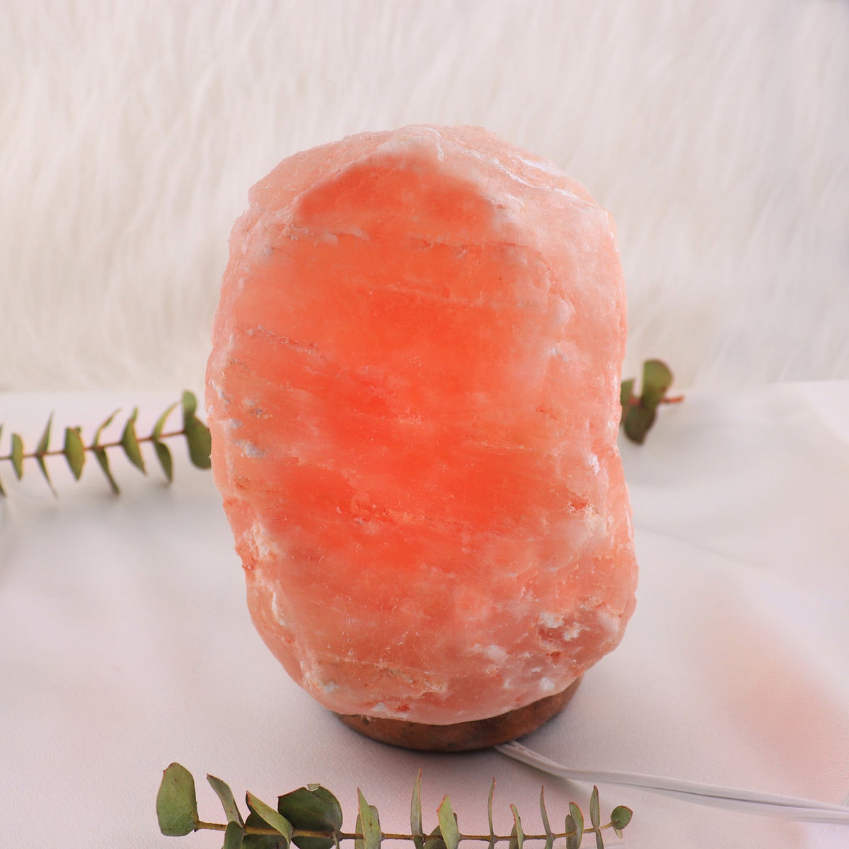 Hand-carved pink Himalayan salt lamp glowing on a wooden base