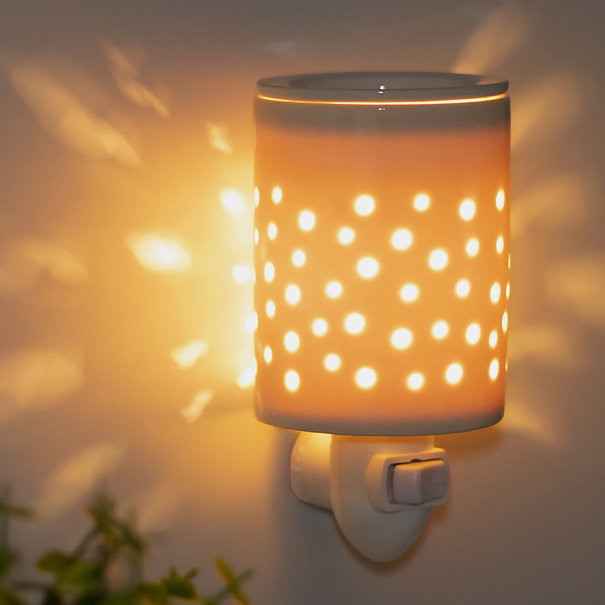Plug-in electric wax melt warmer plugged into a wall outlet