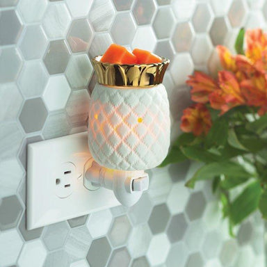 Plug-in electric wax melt warmer plugged into a wall outlet